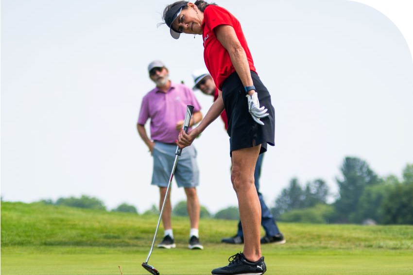 golfer putting while teammates watch at the Cardinal Legacy Golf Outing